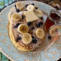 Blueberry-Banana Pancakes · Two large buttermilk pancakes with blueberry, bananas, syrup, and butter.