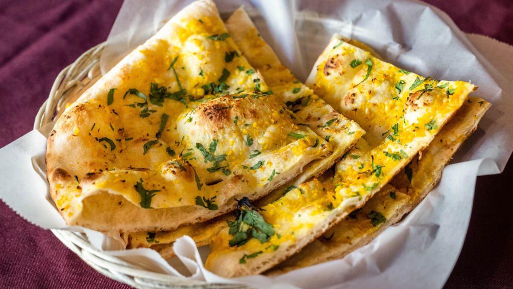 Garlic Naan · Fresh bread cooked in a clay oven topped with minced garlic and cilantro.