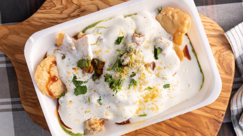 Papdi Chaat · Crunchy base of papadi (crisp puris) topped with yogurt red and mint chutney potatoes chickpeas seav and spices.