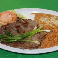 Mexican carne Asada Plate · Beef slices   served with rice, refried beans, grilled onions, lettuce, sour cream, guacamol...