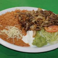 Bistec Encebollado · Beef sautéed in onions and seasonings. Served with rice, refried beans, cheese, lettuce, gua...