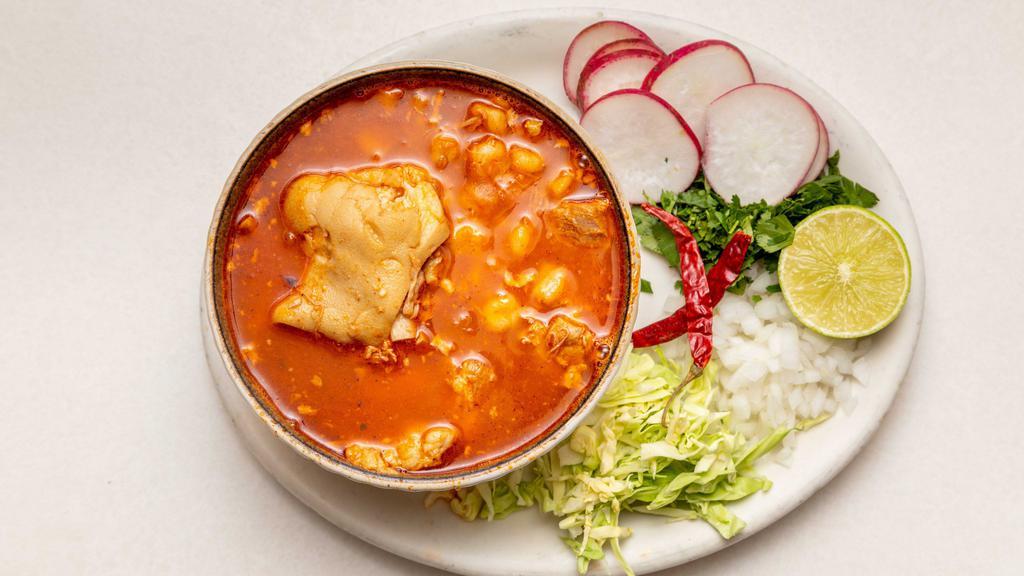 Pozole · Pozole is made with hominy,  and meat,  pork. The stew is seasoned with a combination of spices, and  topped with garnishes radish, cabbage and lime juice, onions cilantro on the side