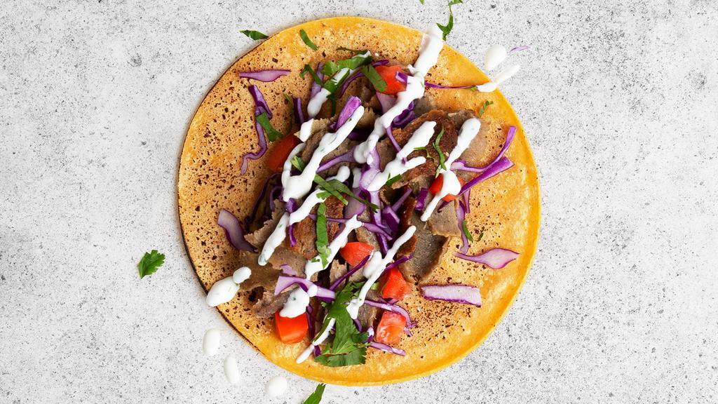 Beef and Lamb Gyro Taco · Flavorful beef and lamb gyro with shredded cabbage, diced tomatoes, cilantro, and tzatziki or tahini in a flour taco.