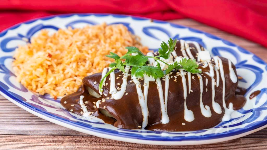 Chicken Enmoladas · Filled with chicken, rolled in mole rojo, topped with sour cream, queso fresco and toasted sesame seeds, served with rice .