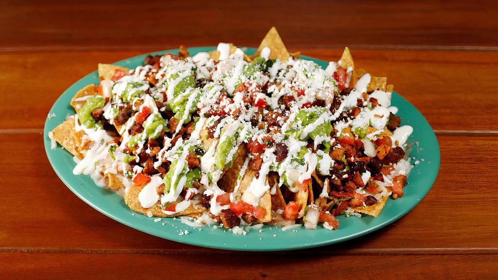 Meat Nachos · Homemade chips topped with Cheese, guacamole, sour cream, salsa fresca and your choice of meat and beans.