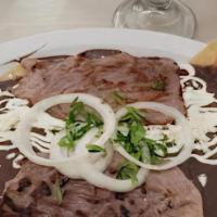 Enfrijoladas · Folded corn tortillas cover in black refried beans, topped with cream, raw onion, cilantro, ...