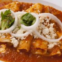 Entomatadas · Corn tortillas cover in red sauce, topped with cream, raw onion, cilantro, queso fresco and ...