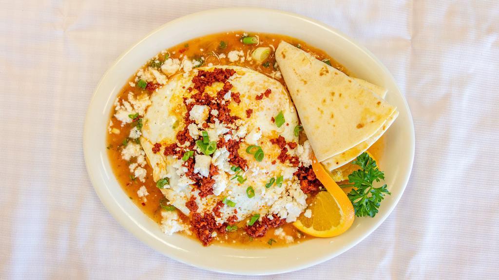 Huevos Rancheros · Two corn tortillas, refried beans, homemade salsa, jack and cheddar cheese, and chorizo. Topped with two eggs, queso fresco, cream, and green onions. Served with one flour tortilla