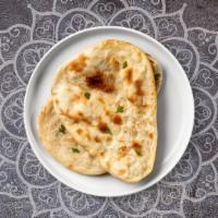 Aloo Naan · Freshly baked bread in a clay oven garnished with potatoes and cilantro.