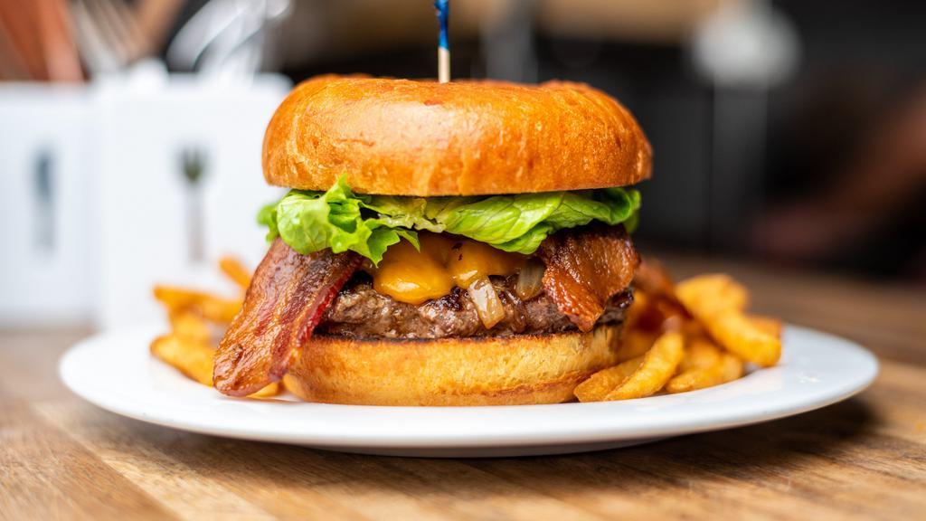 The Westerner · Pacific coast brioche bun with 7 oz Harris ranch grass-fed beef patty, applewood smoked bacon, cheddar cheese, grilled onions, and lettuce. With house BBQ sauce.