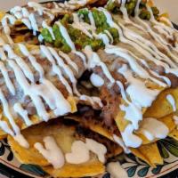 Nachos Super · Chips topped with refried beans, melted cheese, guacamole, crema, salsa fresca, and jalapeno...