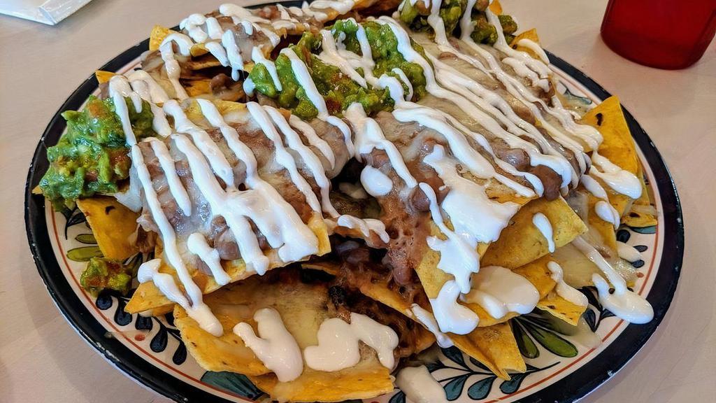 Nachos Super · Chips topped with refried beans, melted cheese, guacamole, crema, salsa fresca, and jalapenos with choice of shredded beef, shredded chicken, angus steak, grilled chicken, or chicken oaxaca.