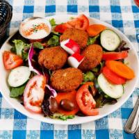 Falafel Salad · Crisp falafel balls over a bed of organic mixed greens, with tomato, cucumber, and vegan tah...