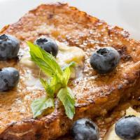 The Blueberry French Toast · Three pieces of fluffy french toasts with fresh blueberries, served with syrup.