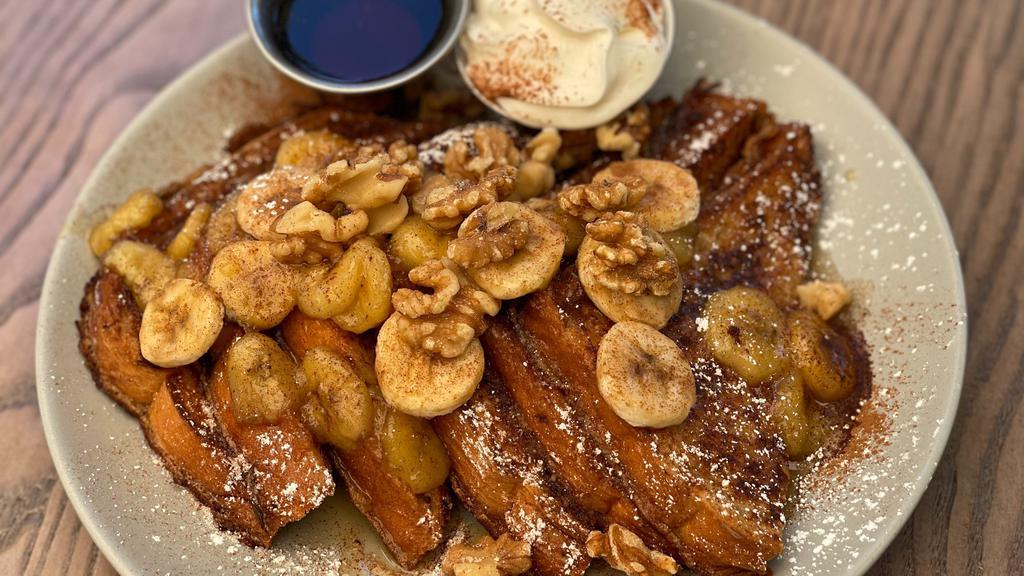French Toast Banana Flambe · 4 pieces of brioche topped with rum-caramelized bananas, fresh banana slices, walnuts, sprinkled with cinnamon & powdered sugar. Served with whipped cream and syrup.