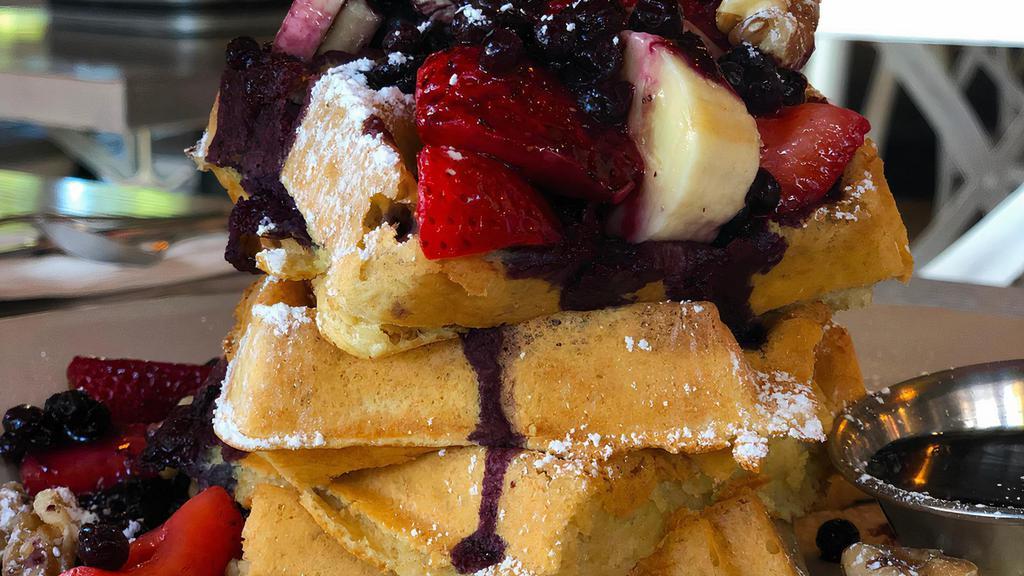 Blueberry Explosion GF Waffle · Giant Belgian Waffle halved, walnuts, fresh blueberries, strawberries & bananas, dusted with powdered sugar & served with a side of house-made compote, syrup & vegan butter.
