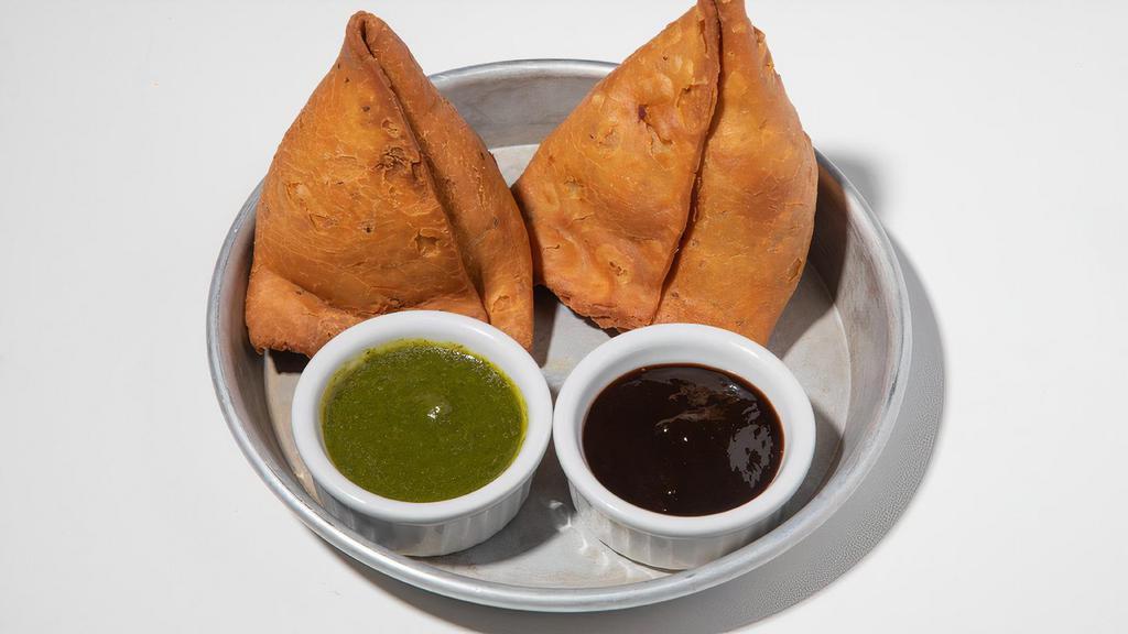Samosas · 2 pieces. Flaky, handmade empanada-like pastries stuffed with curried potatoes. Served with chutneys. Vegan. Contains gluten and dairy. We cannot make substitutions.
