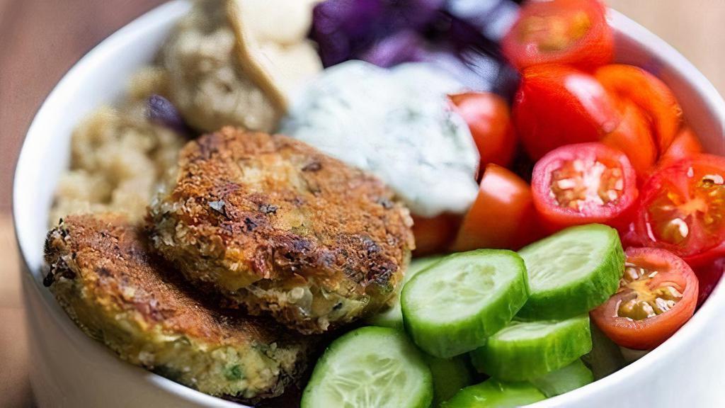 Falafel Rice Bowl · Crispy falafel over basmati rice with hummus, diced cucumber, tomato salad, shredded green cabbage, and a drizzle of tahini sauce.