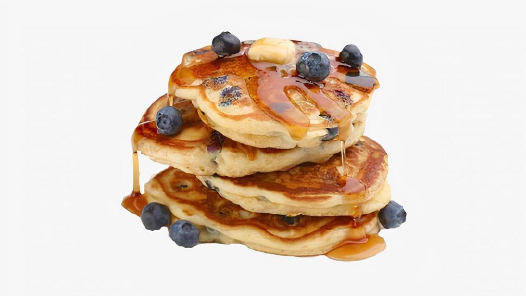 Blueberry Pancakes · Three fluffy pancakes topped with fresh blueberries, and served with syrup and powdered sugar.