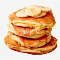 Banana Pancakes · Three fluffy pancakes topped with sliced bananas, and served with syrup and powdered sugar.