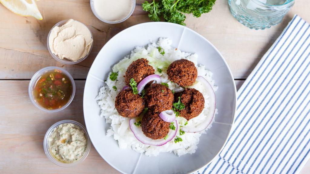 Falafel Platter With Rice · Fresh made golden fried falafel topped with our homemade white sauce on a bed of fluffy basmati rice, seasoned chick peas, and a salad.