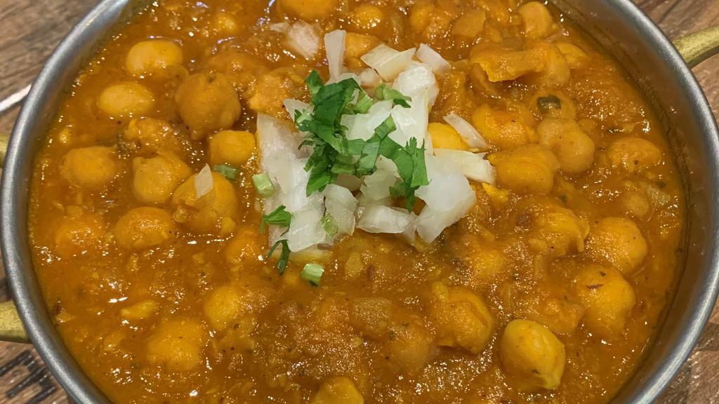 Chana Masala · Vegan, Gluten-Free. Chickpeas beans prepared with a blend of pomegranate seeds, dry mango, carom (Ajwain). black peppercorns, and garnished with ginger.
