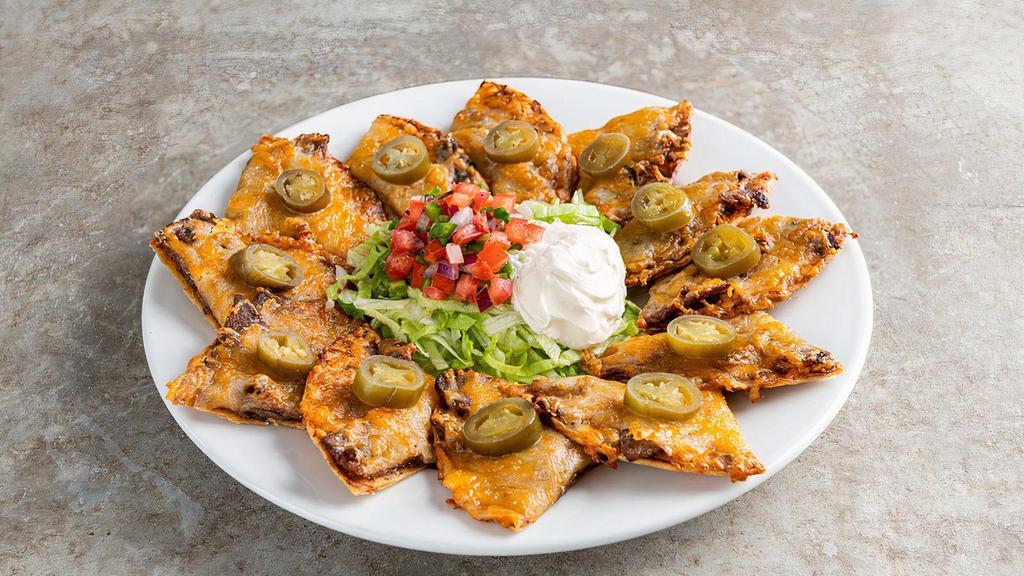 Classic Nachos With Beef · Beef, shredded cheese, black beans, jalapeños, Skillet Queso with beef. Served with pico & sour cream.