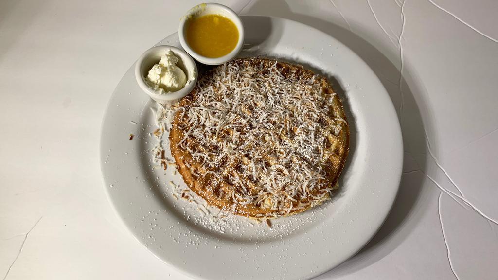 Coconut Waffle · Our golden brown waffle filled and topped with toasted coconut and lightly dusted with powdered sugar, served with whipped butter and hot tropical syrup.