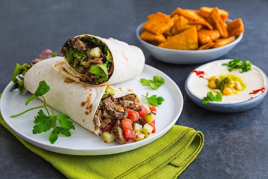 Traditional Steak Shawarma Wrap · Marinated and grilled steak shawarma in light and soft wrap bread. Comes with hummus, tomato cucumber mix, diced pickles, sumac onions and tahini sauce.