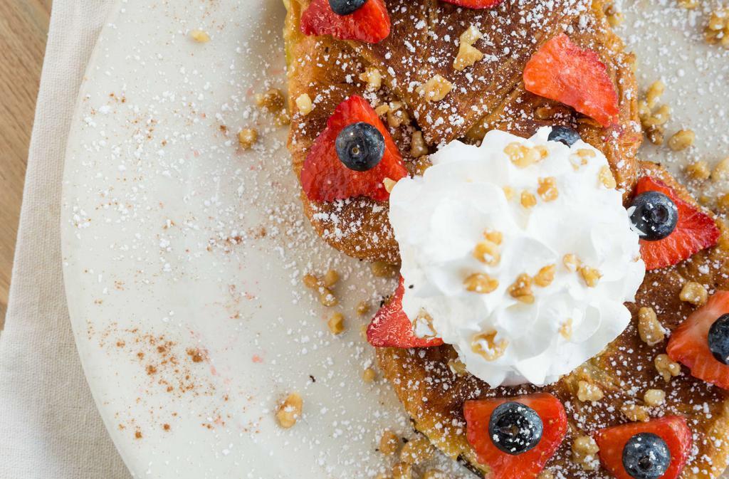 Fancy French Toast · Croissant French toast, topped with mixed berries, roasted walnuts, whipped cream, and powder sugar.