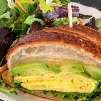 Vegetarian Croissant Egg Sandwich · Egg, gruyere cheese, avocado, greens, and harissa sauce on a croissant.
