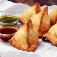Vegetable Samosas · Two homemade pastry shells stuffed with pea and potatoes roasted in cumin.