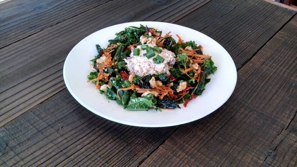 Rosemary Chicken Salad · Rosemary Soy Chicken salad on a bed of massaged kale salad with almonds strawberries, and Balsamic dressing