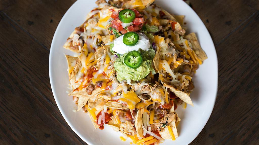 NACHOS GRANDE W/ CHICKEN · A heaping platter of chips topped with chicken, melted cheese, black beans, red sauce, fresh guacamole, sour cream and roasted corn salsa.