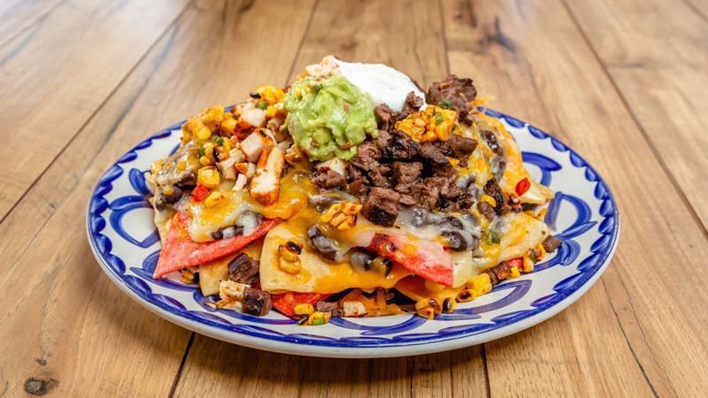 NACHOS GRANDE COMBO · A heaping platter of chips topped with chicken and steak, melted cheese, black beans, red sauce, fresh guacamole, sour cream and roasted corn salsa.