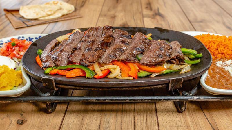 SKIRT STEAK FAJITAS · Citrus-chile marinated and mesquite-grilled skirt steak* served sizzling at your table.