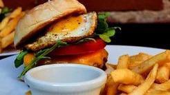 New Zealand Style Gourmet Beef & Lamb Burger · House made beef and lamb patty, with pickled beet, melted Cheddar, tomato, arugula and a fried egg. Comes with a side of fries and BBQ sauce.