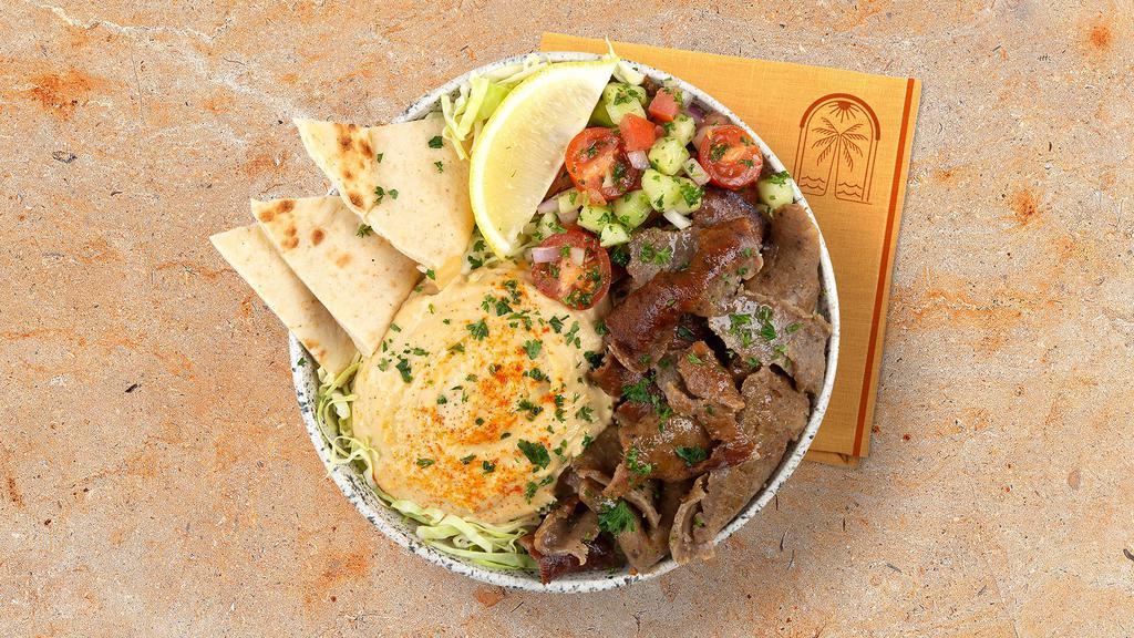 Beef and Lamb Gyro Hummus Bowl · Marinated beef and lamb over hummus, diced cucumber and tomato salad, shredded green cabbage and a drizzle of tahini sauce.