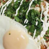 Chilaquiles Rojos · Tortilla drenched in spicy Red salsa, cilantro, sour cream, fresh cheese and two scrambled e...
