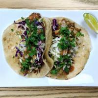Tacos · Two tacos made with heirloom corn tortillas, tomato salsa, cabbage, onion, cilantro, and cho...