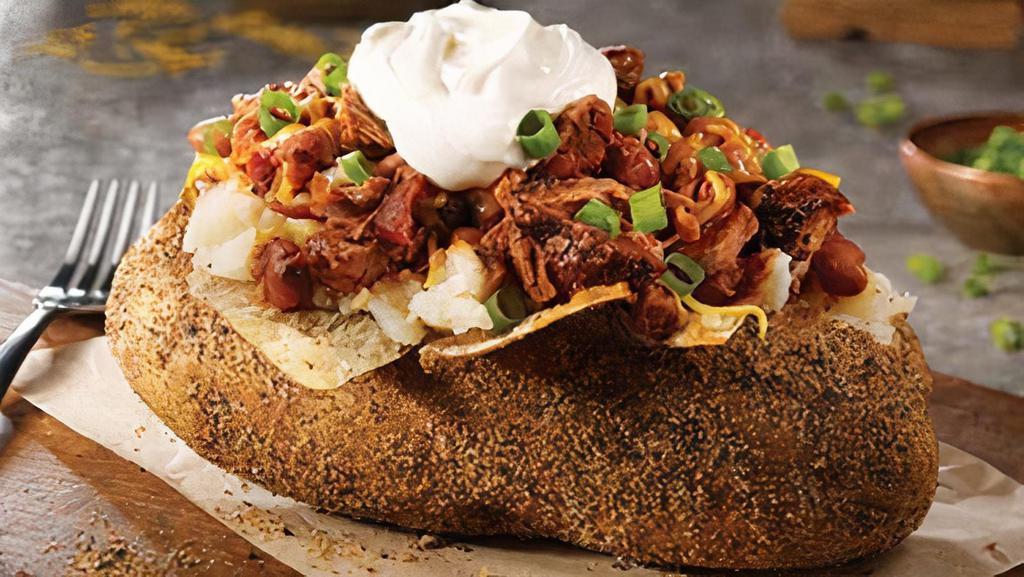 Brisket Chili Baker · A giant smoked baker with margarine, sour cream, shredded cheddar cheese, green onions, and topped with our Brisket Chili.