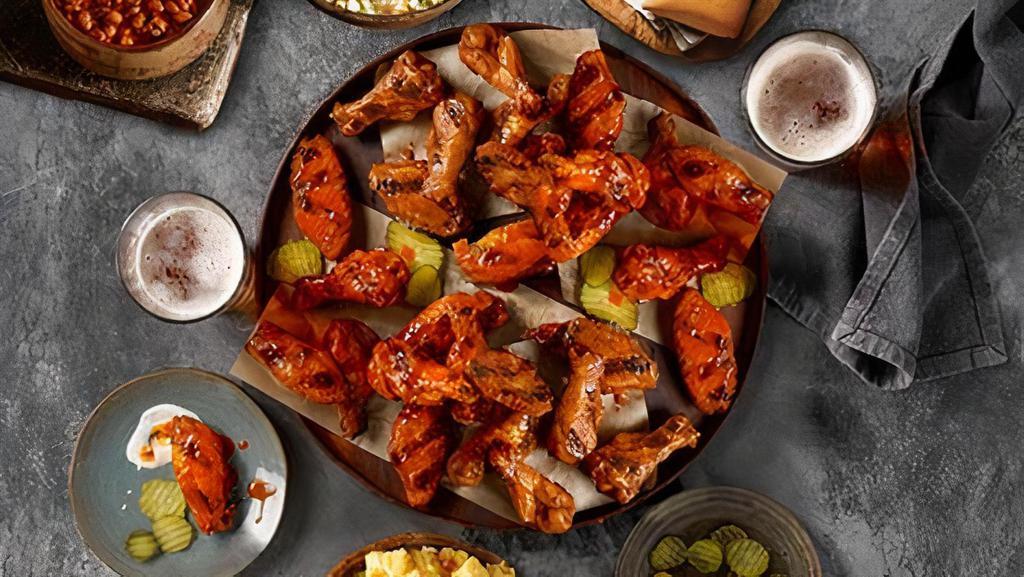Wing Family Pack · The Wing Family Pack includes 24 smoked chicken wings (12 flats, 12 drummies), topped with your choice of sauce, and one of each medium side: potato salad, cabbage slaw, and barbecue beans. Served with six rolls, ranch dressing, pickles and onions.  Feeds
