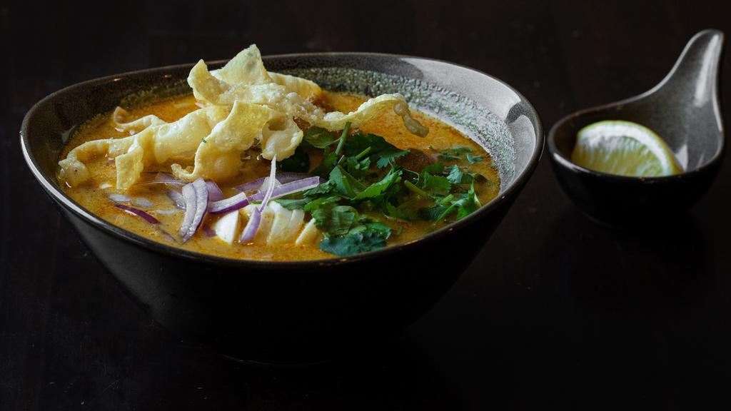 Ohn-No Khao Swe · Coconut noodle soup. A rich and creamy bisque with flour noodles. Served with chicken, onions, turmeric powder, paprika, and garnished with onions, cilantro, and lemon.
