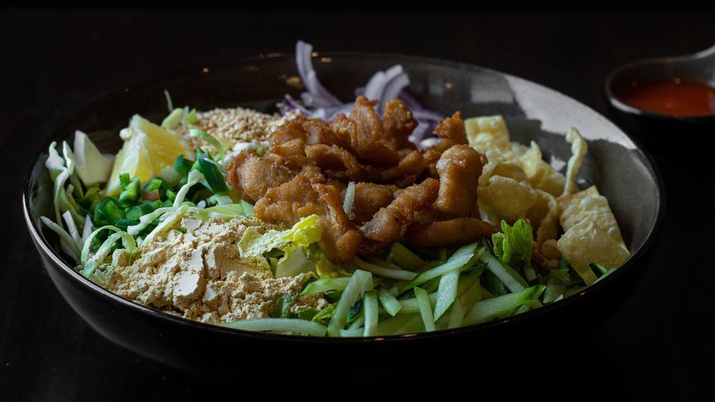 Burmese Chicken Salad · Bite-sized fried chicken with red onions, yellow bean powder, cabbage, cilantro, fried wantons, fried onions, sesame seeds, onion oil and chili sauce on a bed of romaine lettuce.