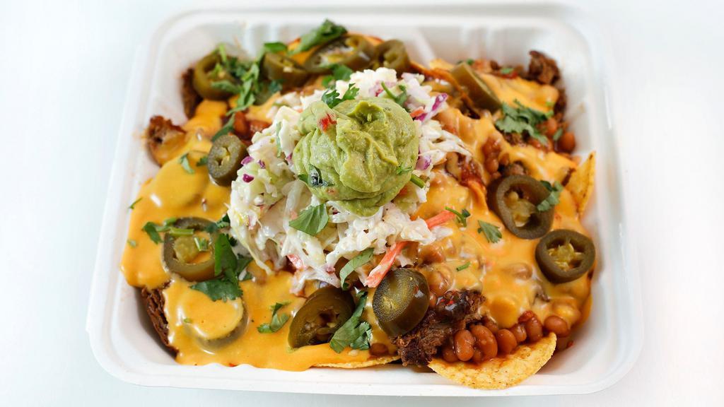 Fully Loaded Mob Nachos · Barbecue seasoned tortilla chips topped with smoked plant-based brisket, nacho cheese, mob sauce, Tasha’s slaw, guacamole, and jalapeños.