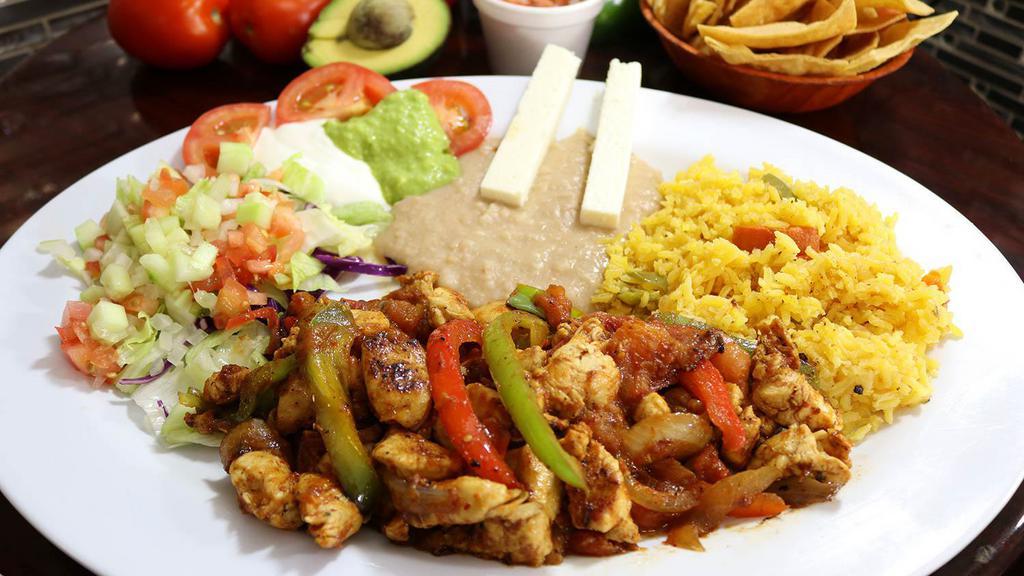Fajitas de Pollo · tender chicken breast strips slightly spiced and cooked with red and green bell pepper, onion, and tomato, served with salad, rice, refried beans, cheese, fresh guacamole, and sour cream.