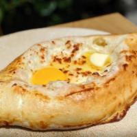 Khachapuri Adjaruli · Boat-shaped bread with cheese, butter and an egg. So good, it made it to our logo.