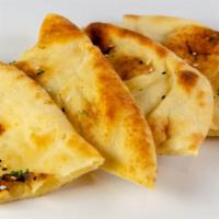 Kulcha Naan · Two pieces of buttered naan, topped with sesame seeds and mint.