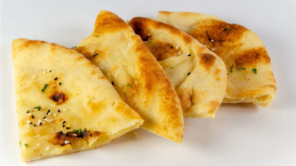 Kulcha Naan · Two pieces of buttered naan, topped with sesame seeds and mint.