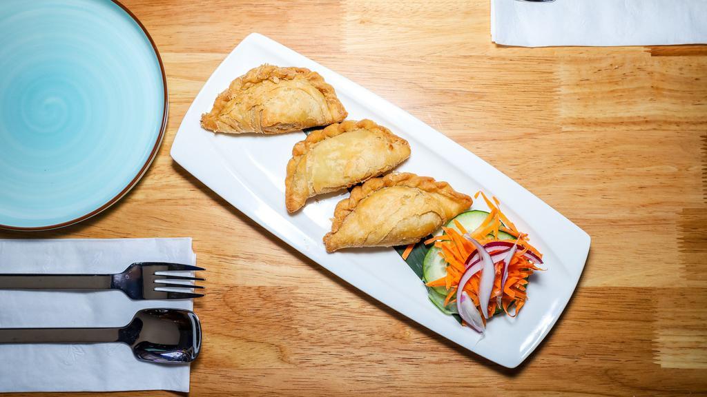 Curry Puff · Deep-fried pastry shell stuffed, curry powder, and potatoes served with a side of cucumber salad and yellow sauce